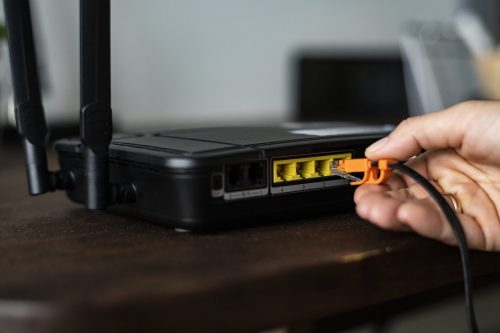 Man plugging in an ethernet cable to a wireless router Man plugging in an ethernet cable to a wireless router